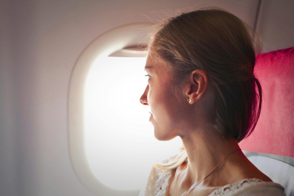 Woman looking out airplane window during flight